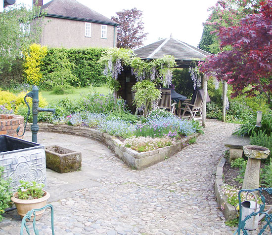 cobbled path, wishing well, bricked walled flower beds